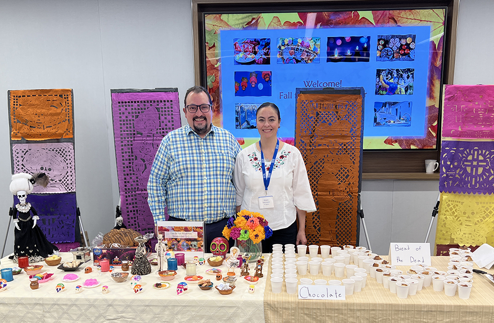 Man and woman stand at table with Day of the Dead items displayed