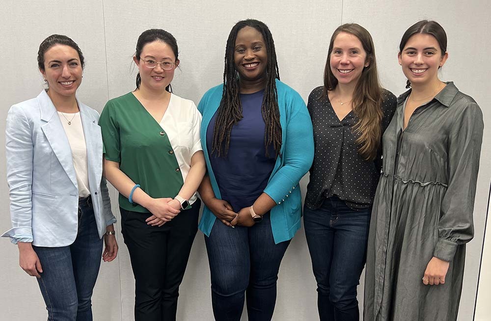 Five women stand and smile at the camera