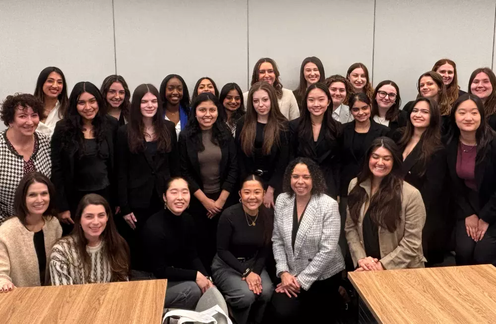A group of 28 smiling women of varying ages pose together, looking at the camera.