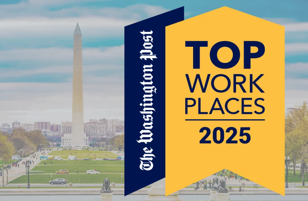 Alt text: An award shield with a yellow and dark blue background. The right component of the shield reads “Top Work Places 2025,” and the left side reads “The Washington Post.” Behind the logo/shield is a background showing the Washington Monument/DC.
