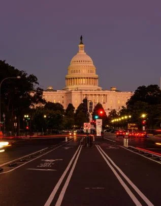 U.S. Capitol Building in the evening with the glow of the streetlights illuminated.
